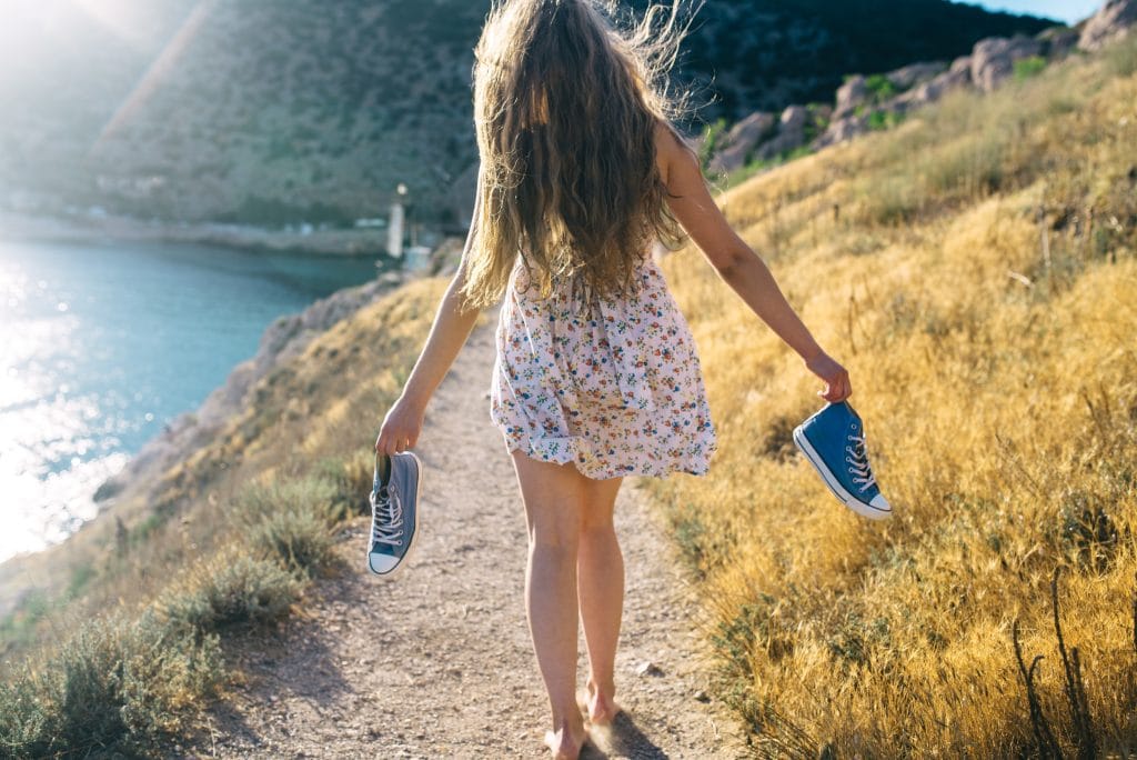 Mädchen mit Schuhen in der Hand in der Natur