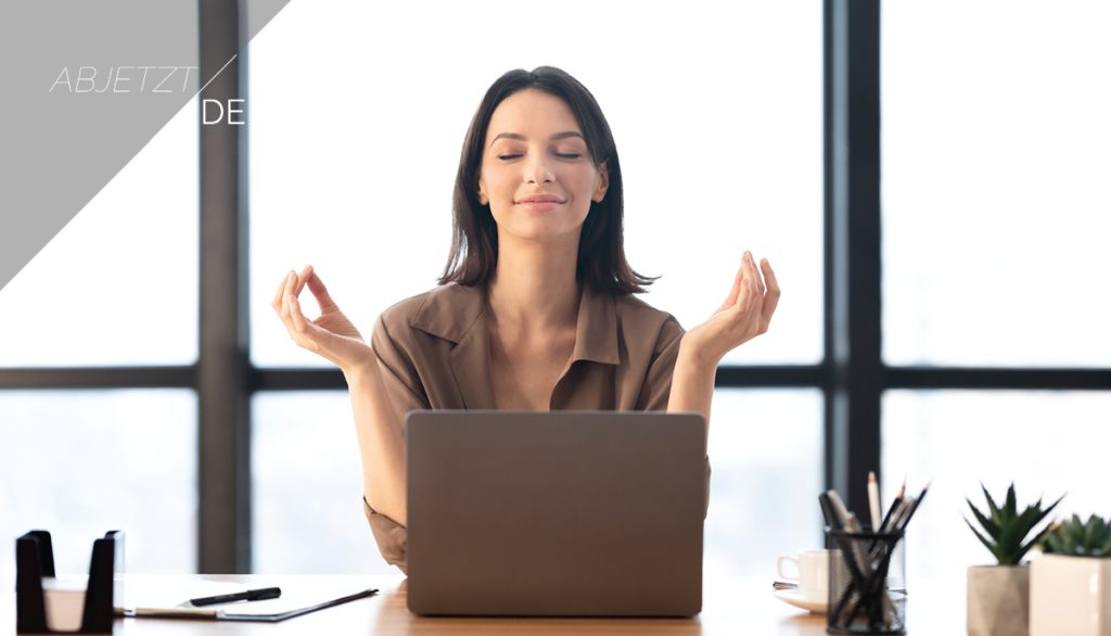 Eine Frau sitzt am Tisch und übt mentale Entspannungstechniken zur Stressbewältigung aus.